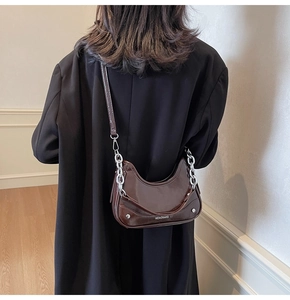 Brown patent leather hobo bag with silver chain detail on model shoulder view
