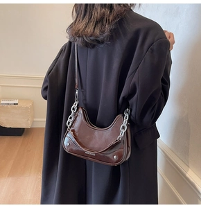 Detail view of deep brown crescent bag with polished finish and silver chunky metal chain