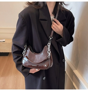 Detail of a brown oil-waxed leather hobo bag with silver chain and brand logo