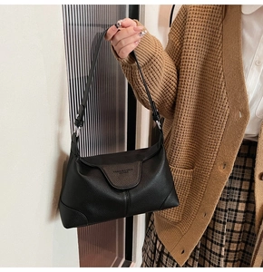 Detail of black lychee texture leather shoulder bag with flap closure and adjustable strap