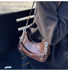 Vue détaillée du sac demi-lune en cuir verni marron avec chaîne argentée et rivets