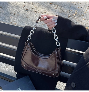 Detail of vintage brown leather underarm bag with silver chain strap and metal rivets