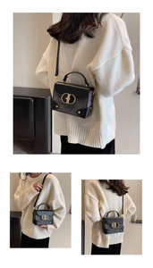 Detailed view of black square crossbody bag with gold CD buckle and textured sides