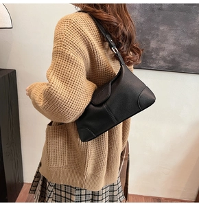 Detail view of black pebble texture and curved flap on minimalist faux leather shoulder bag