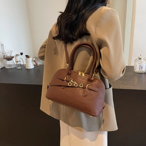 Brown lychee leather tote bag with gold ring buckle worn by model in a cafe setting