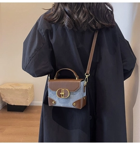 Detail of vintage denim and brown leather crossbody bag with gold hardware and rivets