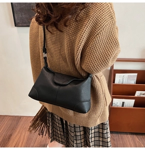 Detail of black pebbled leather underarm tote bag shown on model with shoulder strap