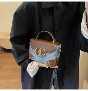 Close-up of the vintage gold buckle on a blue denim and brown leather patchwork handbag