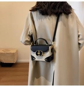 Detail of vintage crossbody bag with gold ring buckle worn over a beige trench coat