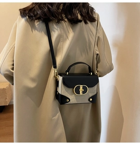 Detail of a chic contrast color square bag with gold metal lock on a khaki coat