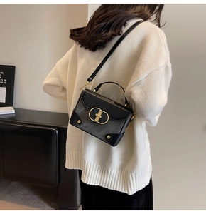 Detail of vintage black square bag with gold CD buckle worn by model on shoulder