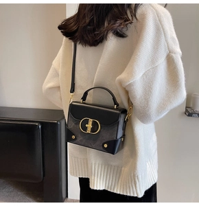 Detail of elegant black crossbody bag with gold CD interlocking buckle and chain strap