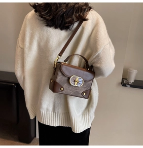 Retro brown leather crossbody bag with gold metal buckle detail on white sweater model
