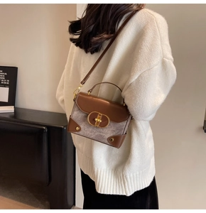Detail of grey fabric bag with brown leather flap and golden oval twist lock closure