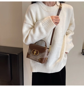 Close-up of contrast leather detail and golden oval lock on vintage grey crossbody bag