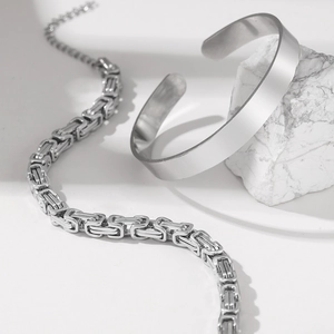 Silver Byzantine chain link bracelet and minimalist C-shaped cuff bangle on stone decor
