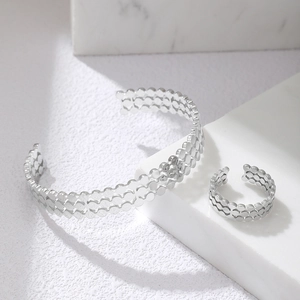 Polished silver stainless steel open cuff bracelet and matching ring set on marble