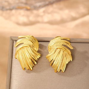 Golden irregular swirl earrings with vintage textured wing design on jewelry box