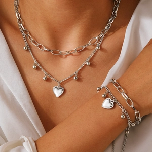 Détail de l'ensemble collier et bracelet double couche en acier avec pendentifs cœur