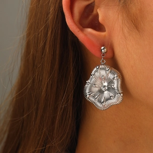 Gros plan de boucles d'oreilles pétales argentées irrégulières avec texture radiale