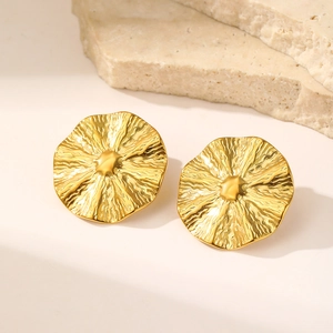 Macro detail of gold round stud earrings with irregular wrinkled texture and organic style