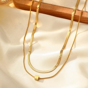 Detailed view of golden double-layer snake chain necklace with a cube pendant on silk