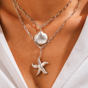 Détail d'un collier double épaisseur argenté avec pendentifs étoile de mer et coquillage
