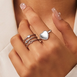 Macro view of stacked silver heart rings on hand with adjustable open band design