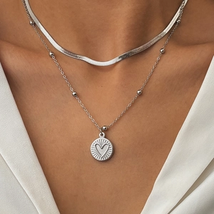 Detail einer silbernen doppellagigen Schlangenkette mit Herzanhänger am Modell