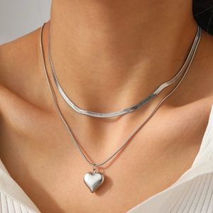 Détail d'un collier double rang en acier inoxydable argenté avec pendentif cœur sur le cou