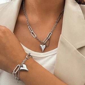 Gros plan sur l'ensemble collier et bracelet à pendentif coeur en acier argenté sur mannequin