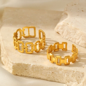 Close-up of gold geometric chain-link open rings displayed on a natural stone base