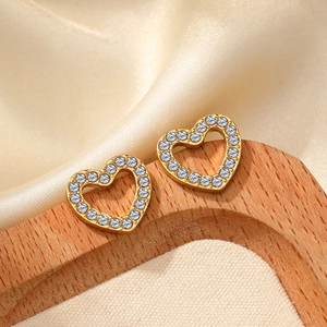 Elegant gold-tone open heart stud earrings with sparkling pavé crystals on silk background