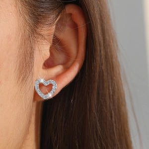 Close-up of a model wearing sparkling heart-shaped hollow earrings with pavé crystals