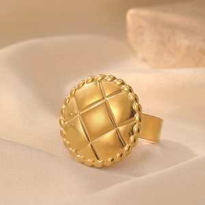 Macro detail of gold vintage signet ring featuring quilted pattern and beaded edge design