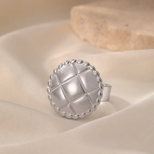 Elegant stainless steel ring with quilted pattern and beaded edge on silk background