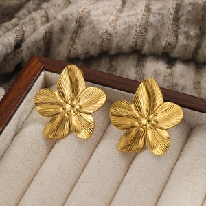 Detailed macro view of 18k gold plated flower stud earrings with hammered texture petals