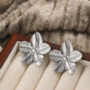 Detailed view of silver flower earrings with hammered texture in a wooden jewelry box