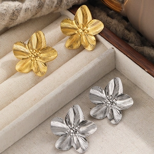 18k gold and silver flower stud earrings with brushed metallic texture in jewelry tray