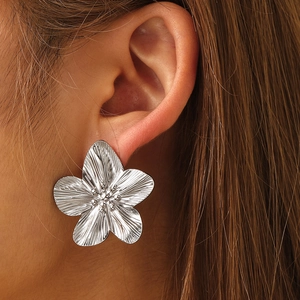 Detail view of large silver flower stud earring with textured metal petals on model
