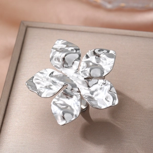 Polished silver five-petal flower ring with hammered texture on elegant jewelry box