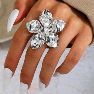 Close-up of a chunky silver flower ring with hammered texture worn on a finger