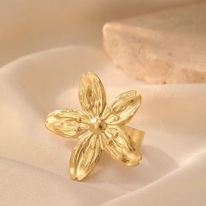 Macro detail of a gold flower ring featuring textured petals and a warm elegant backdrop