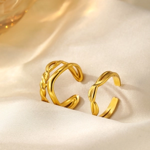 Detail of gold woven twisted open rings on beige silk fabric with natural soft lighting