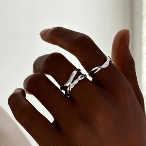 Detailed view of polished silver twisted rope and wavy stackable rings on a finger