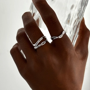 Minimalist silver braided twisted ring set for women on model holding glass