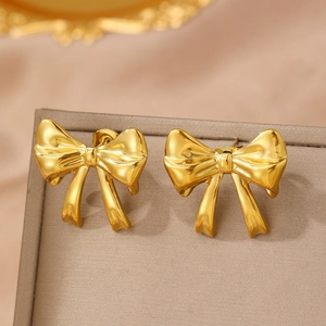 Polished gold bow earrings with a minimalist knot design on a satin jewelry box