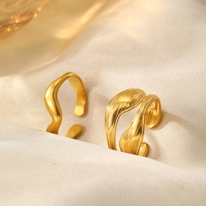 Detail of adjustable gold waved rings with lava texture on white satin fabric