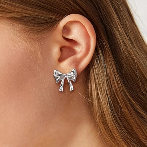 Close-up of model wearing stylish silver bow knot stud earrings in stainless steel