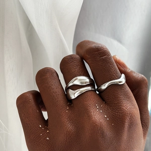 Macro detail of irregular silver wavy rings with liquid metal texture on hand